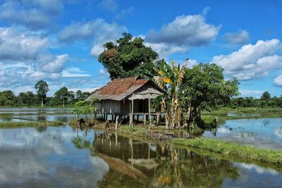 House by lake and trees against sky