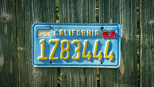 Weathered and worn california license plate hanging on wooden fence