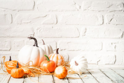 Close-up of pumpkins on table against wall