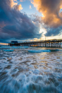 Pier over sea against sky during sunset