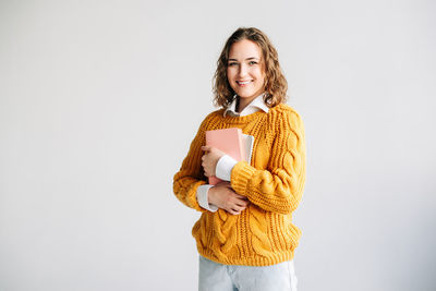Portrait of young woman standing against white background