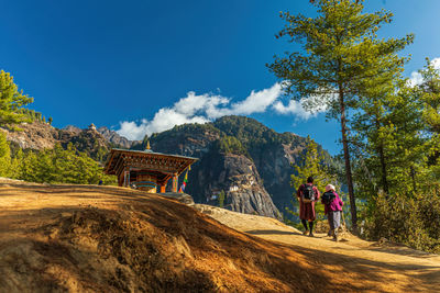 Rear view of people walking on mountain against blue sky