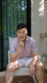 Portrait of man siting on seat against window