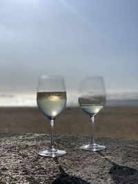 Close-up of wine glass on beach against sky