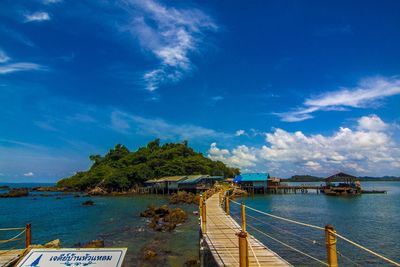 Footbridge over sea against blue sky