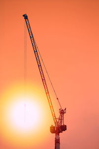 Silhouette cranes against romantic sky at sunset