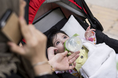 Mother talking on mobile phone while daughter drinking milk from bottle 