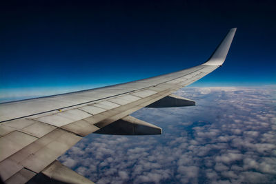 Airplane flying over clouds against blue sky