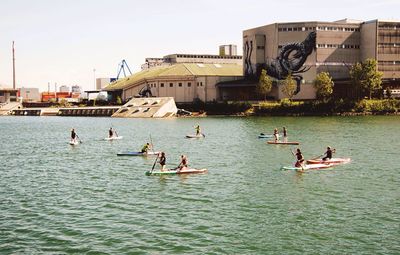 People on river by buildings in city