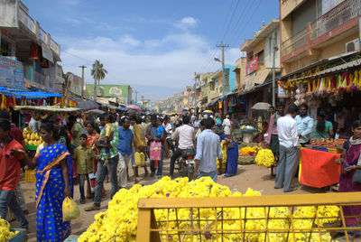 People at market in city against sky