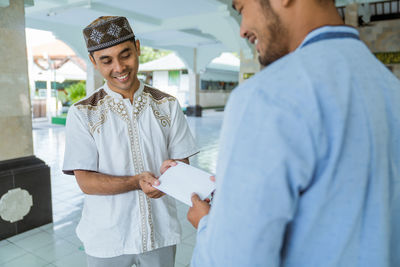 Smiling mosque receiving envelope at mosque