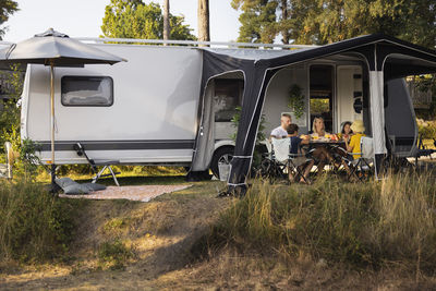 Family relaxing in front of camper trailer