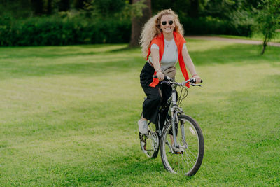 Portrait of woman with bicycle on field