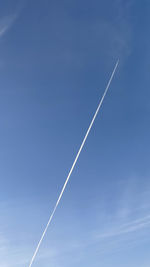 Low angle view of vapor trail against blue sky