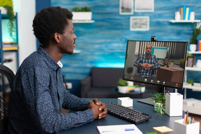 Side view of young man using laptop on table