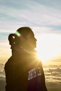 Close-up of girl standing against sky during sunset