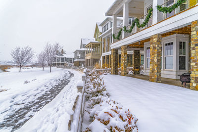 Snow covered houses by building against sky