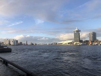 Sea by modern buildings against sky in city