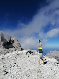 Rear view of man standing on mountain against sky