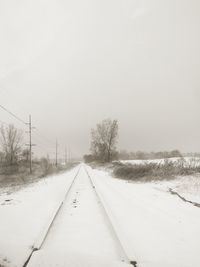 Road amidst snow covered landscape against sky