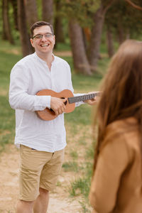 Man and a woman in love embrace and walk in nature. a man plays guitar or ukulele 