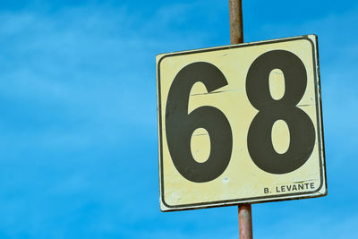 Low angle view of road sign against blue sky