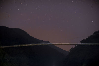 Bridge over river against sky at night