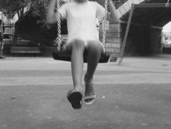 Rear view of girl jumping in front of building