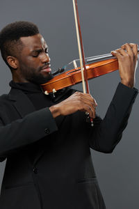 Midsection of man playing violin against white background