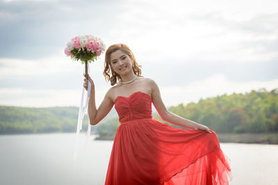 Portrait of a beautiful young woman holding red flower