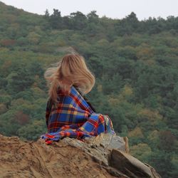 Rear view of woman sitting on mountain