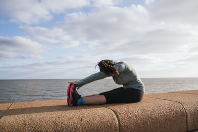 Woman sitting down stretching her legs.