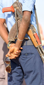 Midsection of man with rifle and sunglasses