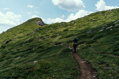 Rear view of man walking on mountain against sky