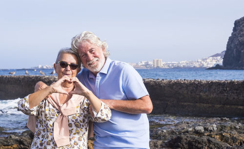 Portrait of smiling senior couple standing by sea