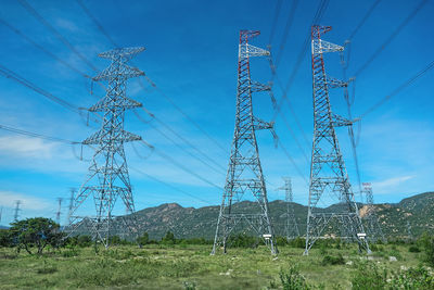 Low angle view of electricity pylon on field against sky
