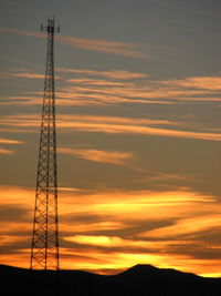 Low angle view of electricity pylon at sunset