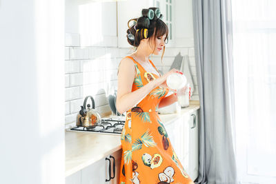 Portrait of woman holding gift while standing at home