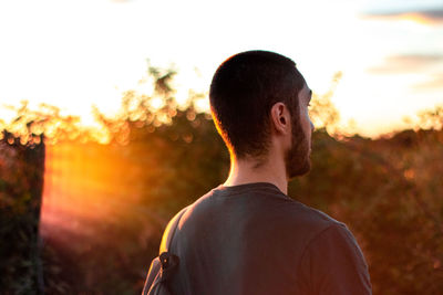 Rear view of man standing against sky during sunset