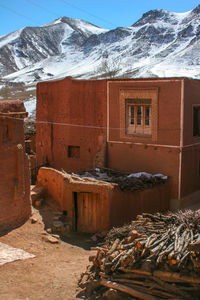 Abandoned building by snowcapped mountain against sky