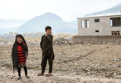 Children standing on field against sky