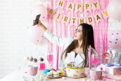 Attractive woman in white party clothes celebrating birthday taking selfie on mobile