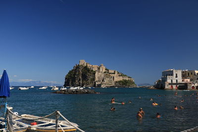 Scenic view of sea by buildings against clear blue sky