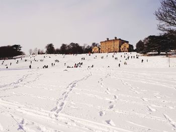 People on snow covered land against sky