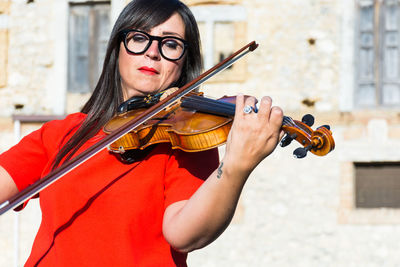 Woman playing violin against building