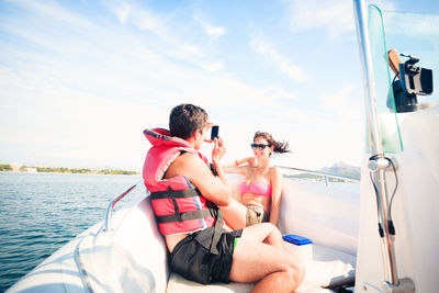 People in boat sailing on sea against sky