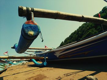 Fishing boat moored at beach against clear blue sky