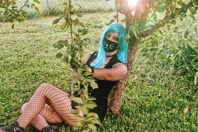Full length of woman wearing mask and stockings by tree
