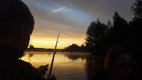 Woman fishing at lake during sunset