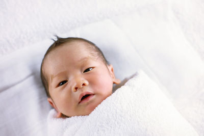 Portrait of cute baby lying on bed